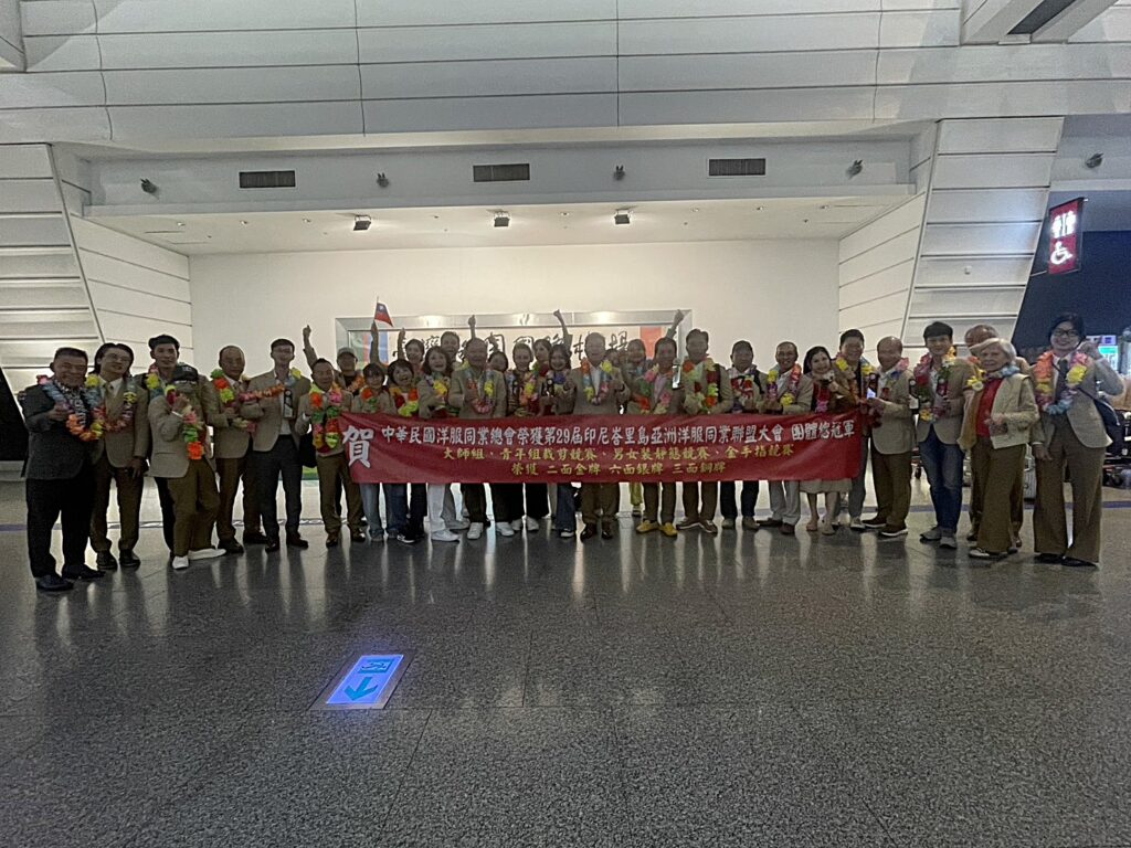 代表團凱旋歸國，於機場拉起紅布條慶祝榮獲團體總冠軍及多項大獎。（圖／臺北市西服商業同業公會提供）